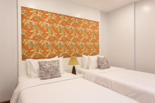 two beds in a room with a painting on the wall at Alisea Pool Villa Aonang in Ao Nang Beach