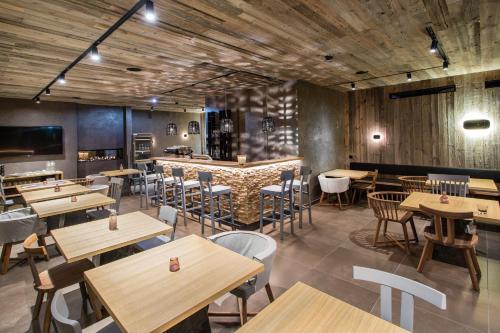 um restaurante com mesas e cadeiras de madeira e um bar em Senses Violett Suites - Adults Only em Zell am See