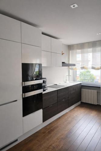 a kitchen with black and white cabinets and a sink at Downtown Boulevard View Residence in Šiauliai