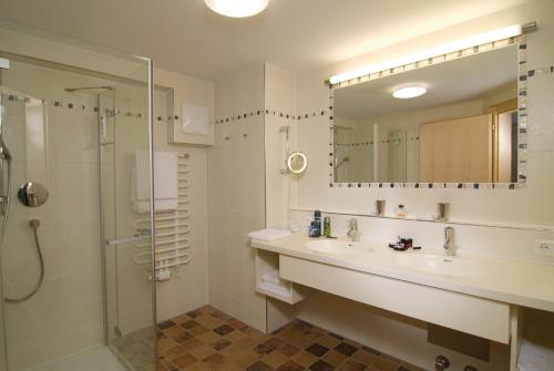 a bathroom with a sink and a shower and a mirror at Appartements Bergsonne in Westendorf