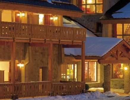 une maison avec une terrasse en bois dans la neige dans l'établissement La Pradella, à Bolquère-Pyrénées 2000