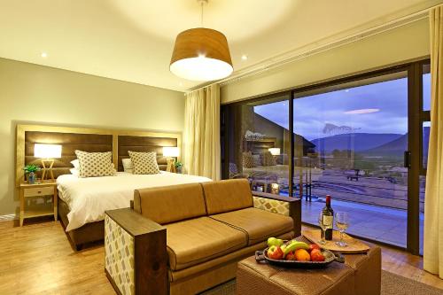 a bedroom with a bed and a couch and a table at Aquila Private Game Reserve & Spa in Touwsrivier