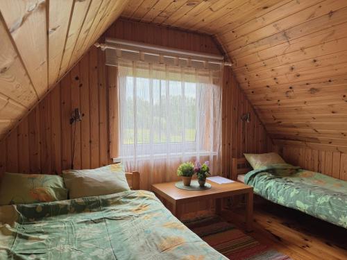 a bedroom with two beds and a table and a window at Diby Kämping saunamaja numbritoad in Diibi