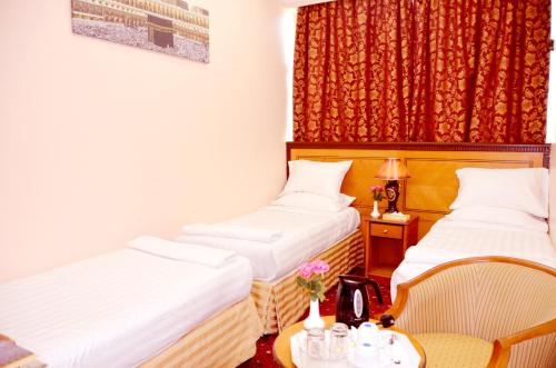 twee bedden in een kamer met een tafel en stoelen bij Anwar Al Deafah Hotel in Mekka