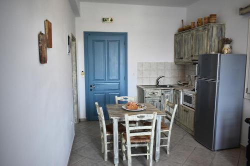 a kitchen with a table with chairs and a refrigerator at Catsalos Studios in Pera Gyalos