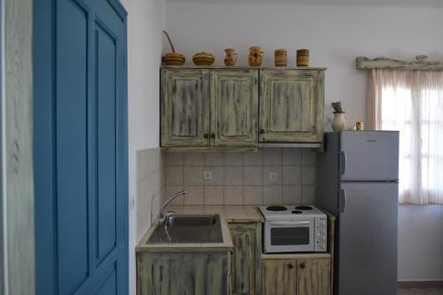 a kitchen with wooden cabinets and a refrigerator at Catsalos Studios in Pera Gyalos