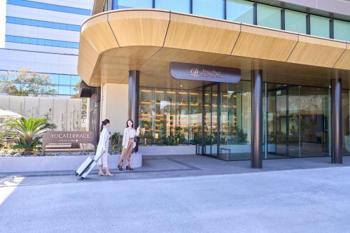 two people walking in front of a building at Fukuoka Prince Hotel Momochihama in Fukuoka