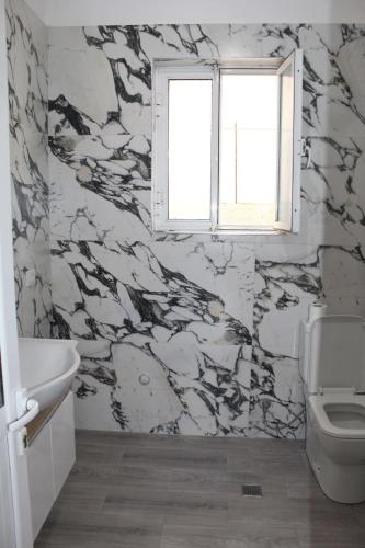 a bathroom with a white toilet and a window at Diar Sea House in Orikum