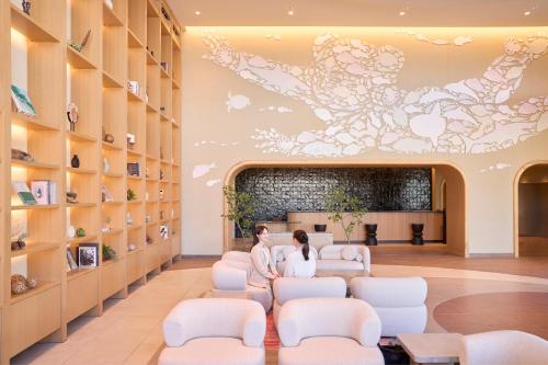 a salon with white chairs and a painting on the wall at Fukuoka Prince Hotel Momochihama in Fukuoka