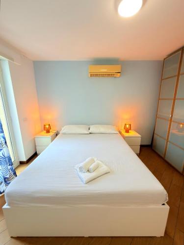 a bedroom with a large white bed with two lamps at Meduse Seafront - Attico al Mare in Torvaianica