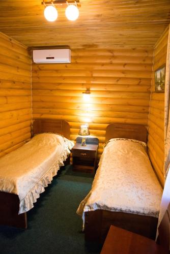 two beds in a room with wooden walls at Gluhoman in Poltava