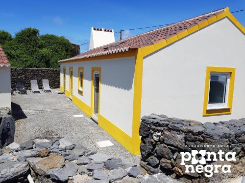 a building with yellow trim and a stone wall at Recanto das 5 by PontaNegraAzores in Cinco Ribeiras