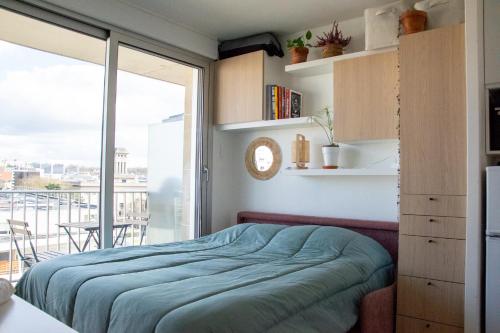 a bedroom with a bed and a large window at Studio avec balcon Centre Ville in Montreuil