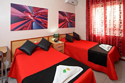 2 camas en una habitación con rojo y negro en Hostal Carrizo, en Elda