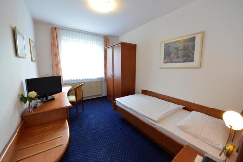 ein Hotelzimmer mit einem Bett und einem Schreibtisch mit einem Computer in der Unterkunft Trollinger Hof in Bad Oeynhausen