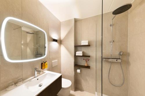 een badkamer met een douche, een wastafel en een toilet. bij Hotel De Bilderberg in Oosterbeek