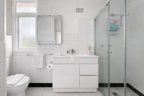 a white bathroom with a toilet and a sink at Sydney Harbour Side Waterfront Apartment in Sydney