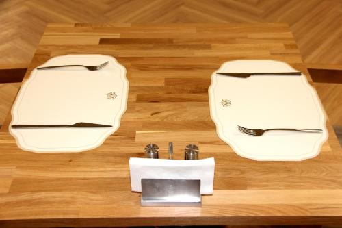 two white dishes on a wooden table with a knife and fork at Linza Suite in Babaeski