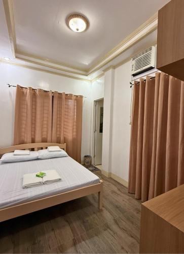 a bedroom with a bed and a window with curtains at Nielo's Apartment Door 4 in Dapitan