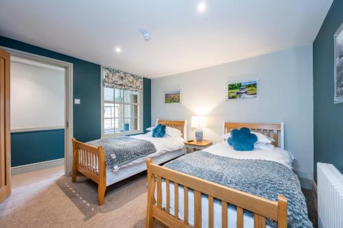 zwei Betten in einem Schlafzimmer mit blauen Wänden in der Unterkunft The Peppermill Boutique Hotel in Devizes