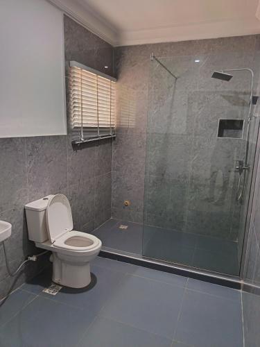 a bathroom with a toilet and a glass shower at Kbazz apartments in Ibadan