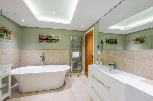 ein Badezimmer mit einer großen weißen Badewanne und grünen Wänden in der Unterkunft The Peppermill Boutique Hotel in Devizes