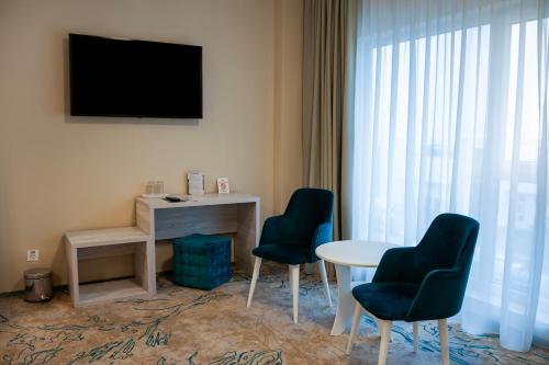 pokój z dwoma krzesłami, stołem i telewizorem w obiekcie Fiald Hotel & Spa w mieście Bacău