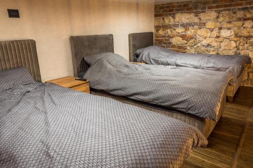 two twin beds in a room with a stone wall at Sky Apartman 2 in Kučevo