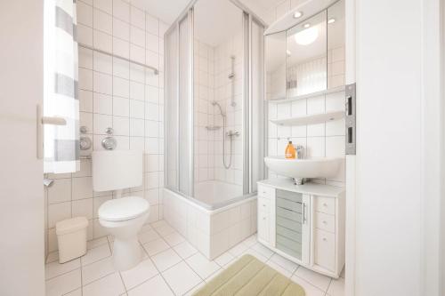 a white bathroom with a toilet and a sink at Boje 15 in Schillig