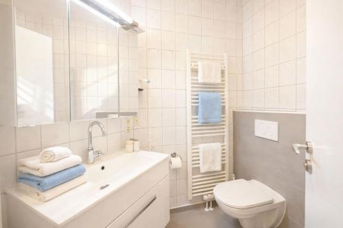 a white bathroom with a sink and a toilet at Boje 5 in Schillig