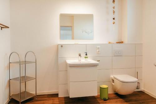 a white bathroom with a sink and a toilet at Vogelkieker in Schillig