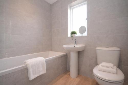 a bathroom with a toilet and a sink and a bath tub at Fossgate Luxury Duplex City Centre Apartment with Free Parking in York