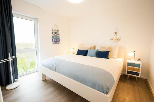 a white bedroom with a large bed and a window at Leuchtfeuer in Schillig