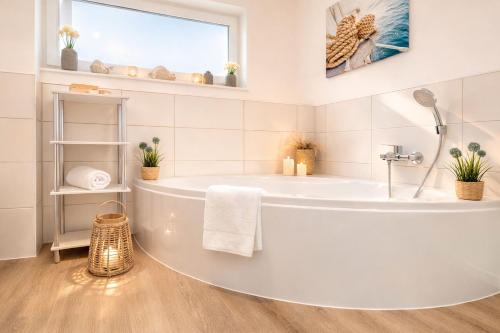 a white bathroom with a tub and a window at Leuchtfeuer in Schillig