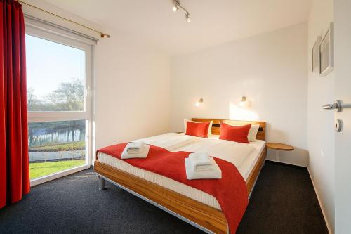 a bedroom with a bed with red pillows and a window at Waterkant in Schillig