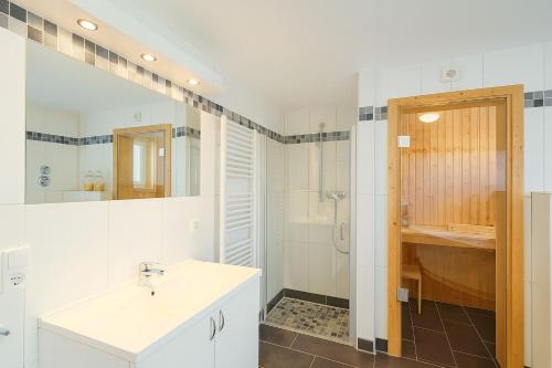 a white bathroom with a sink and a shower at Waterkant in Schillig