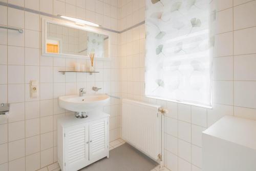 a white bathroom with a sink and a mirror at Boje 9 in Schillig
