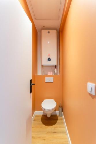 a bathroom with a toilet with an orange wall at Lavagnou Duplex in La Ciotat