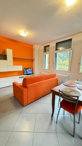 a living room with an orange couch and a table at Dimora delle Terme in Porretta Terme