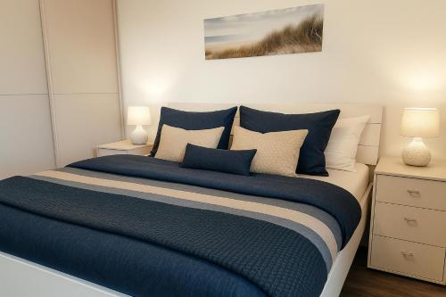 ein Schlafzimmer mit einem Bett mit blauen Laken und Kissen in der Unterkunft Weitblick in Schillig