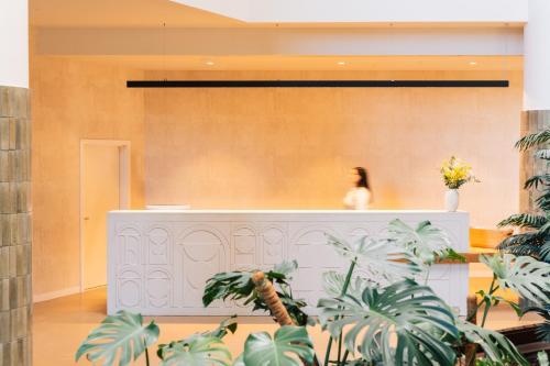 a woman standing behind a counter in a room with plants at Falésia Hotel - Adults Only in Albufeira