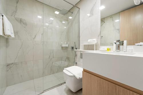 a bathroom with a toilet and a glass shower at FIRST CLASS Studio Beach View Living Bliss in Ras al Khaimah
