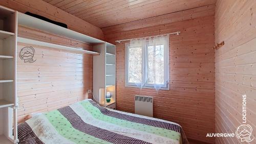 a bedroom with a bed in a wooden room at Chalet de la Gougère 3 in Chambon-sur-Lac