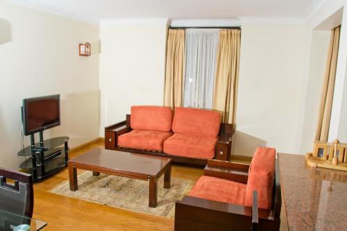 a living room with a couch and a tv at Natural Oak Apartments in Nairobi