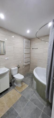 a bathroom with a tub and a toilet and a sink at B apartment Рахів in Rakhiv