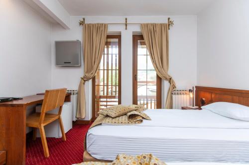 a bedroom with a bed and a desk and a computer at Garni Konak Hotel By Blanket Collection in Sarajevo