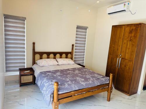 a bedroom with a bed and a wooden dresser at Zara Homes in Alleppey
