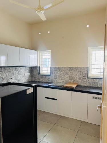 a kitchen with white cabinets and black counter tops at Zara Homes in Alleppey
