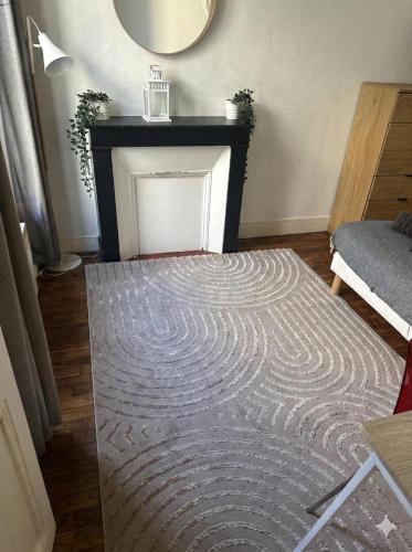 a living room with a fireplace and a rug at Paris Défense T2 Design in Suresnes