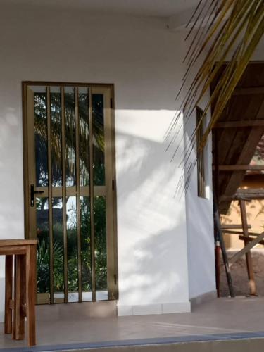 an open door of a white building with a wooden bench at Campement les Baobabs Abene in Abémé